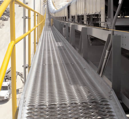 A long walkway made from the diamond safety grating close to the transportation track.